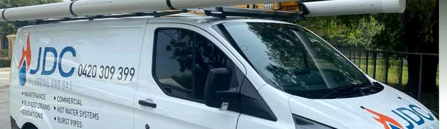 White JDC Plumbing and Gas service van with blue branding, phone number 0420 309 399, and services listed on the side.